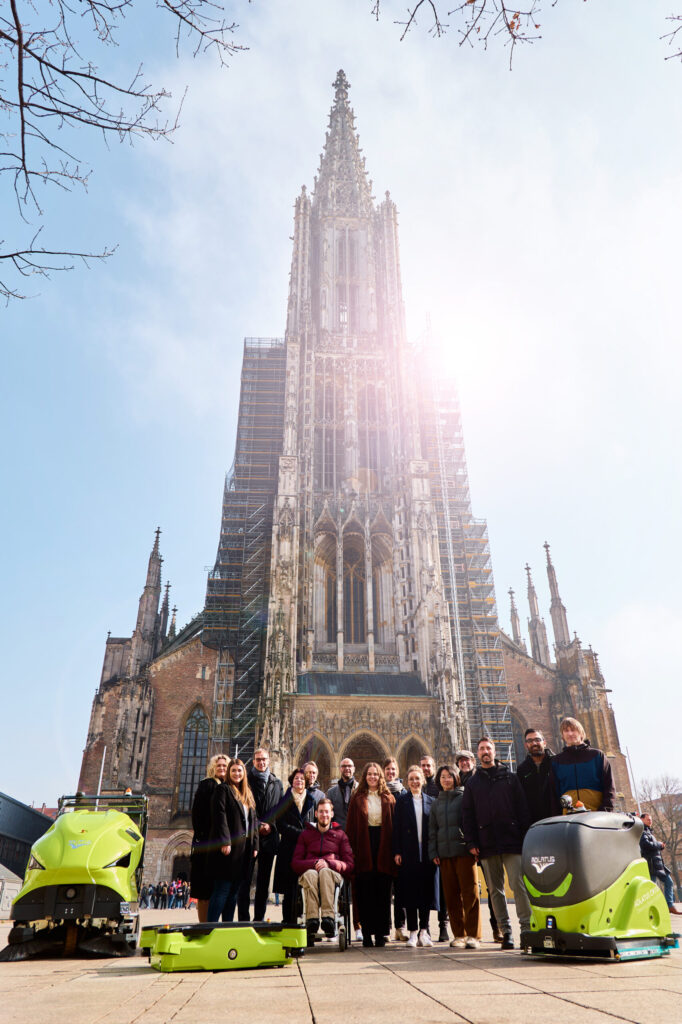 The members of the ZEN-MRI consortium with robots in front of the Ulm Minster (photo/©: Thomas Abé)