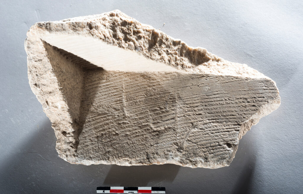 Carbonate fragment from the Barbegal mills, formed on wood of the mill machinery, with imprints of wood and traces of woodworking (photo/©: Philippe Leveau)